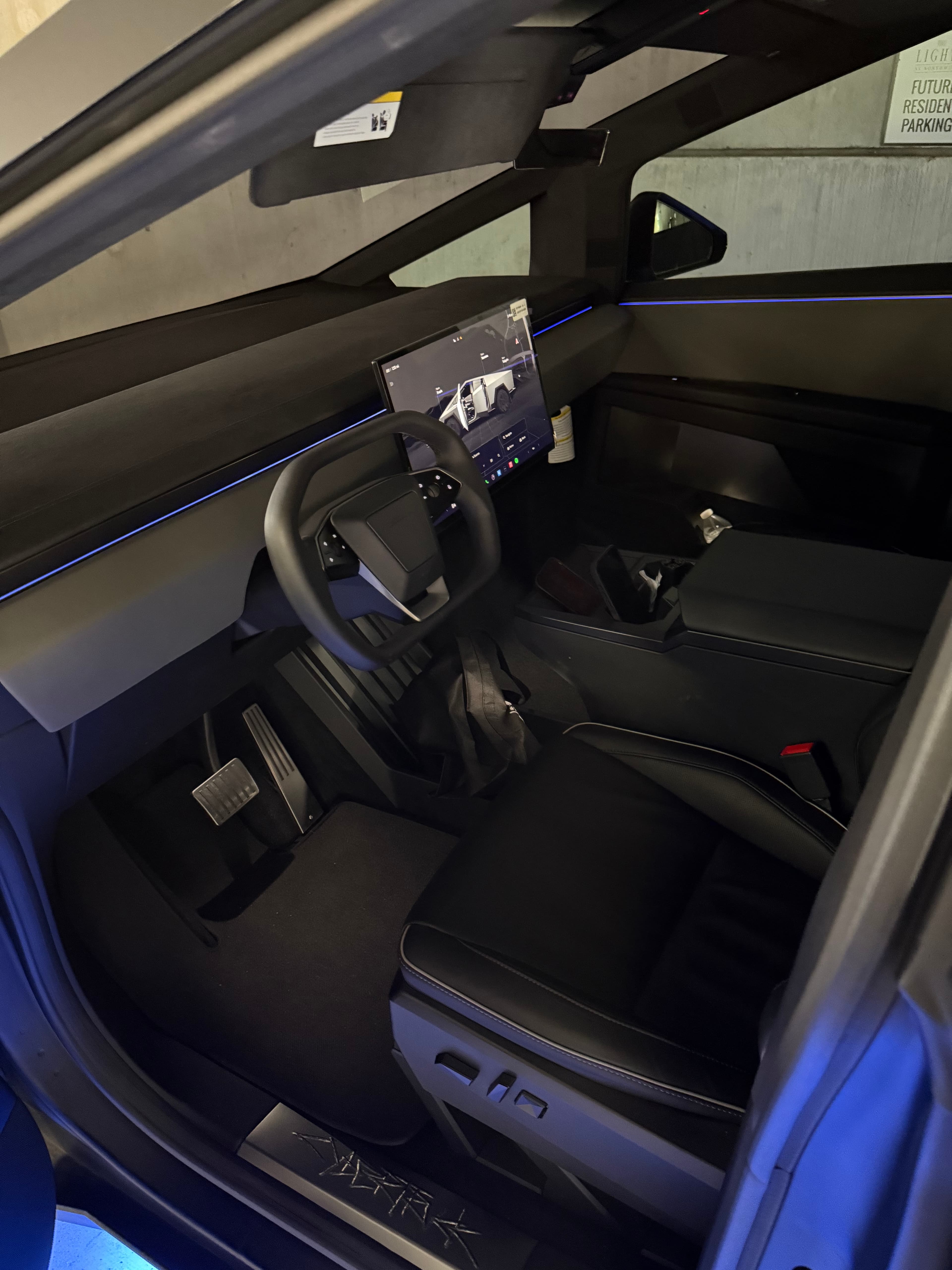 Tesla Cybertruck interior with a minimalist dashboard, yoke steering wheel, and large central touchscreen.
